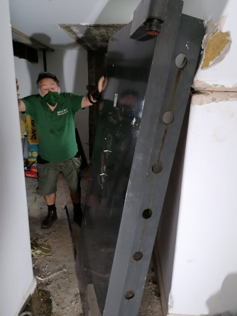 Vault door removed and resting on a wall